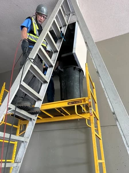 Technician preparing elevated access for multi-unit drainage-stack cleaning