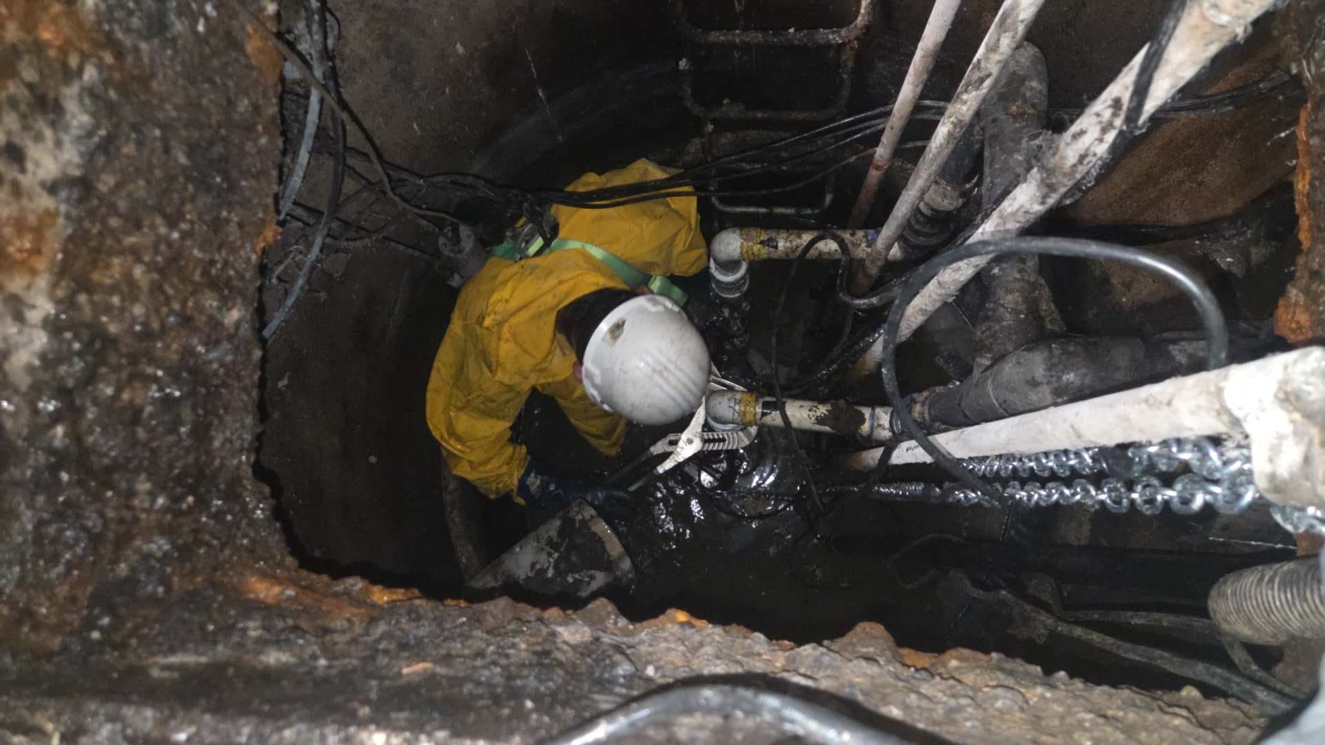 Technician servicing equipment inside a sump vault