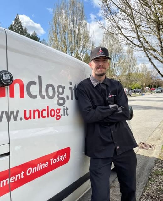 A technician beside an Unclog.it service vehicle
