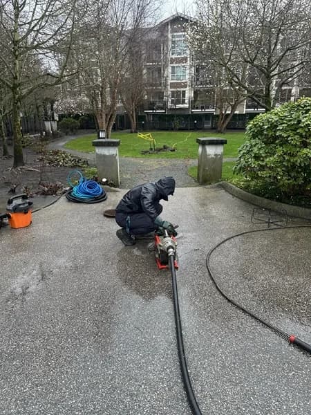 Technician accessing exterior drainage piping during a catch-basin investigation