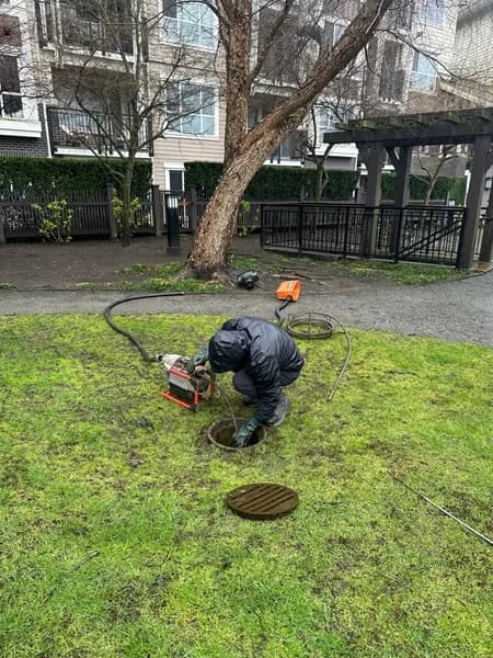 Technician clearing a blocked catch basin during an exterior drainage investigation