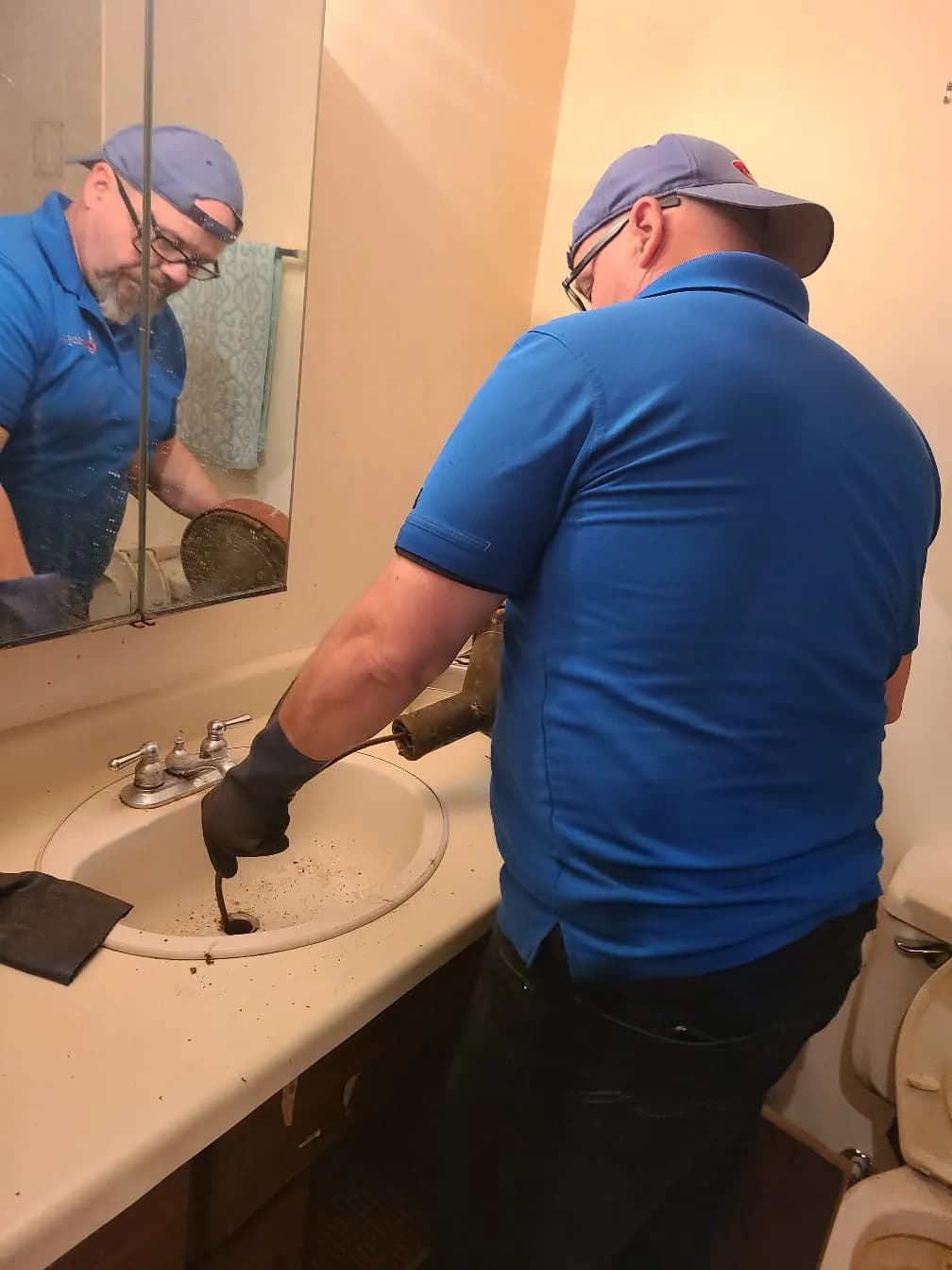 Technician clearing a fixture drain in a bathroom