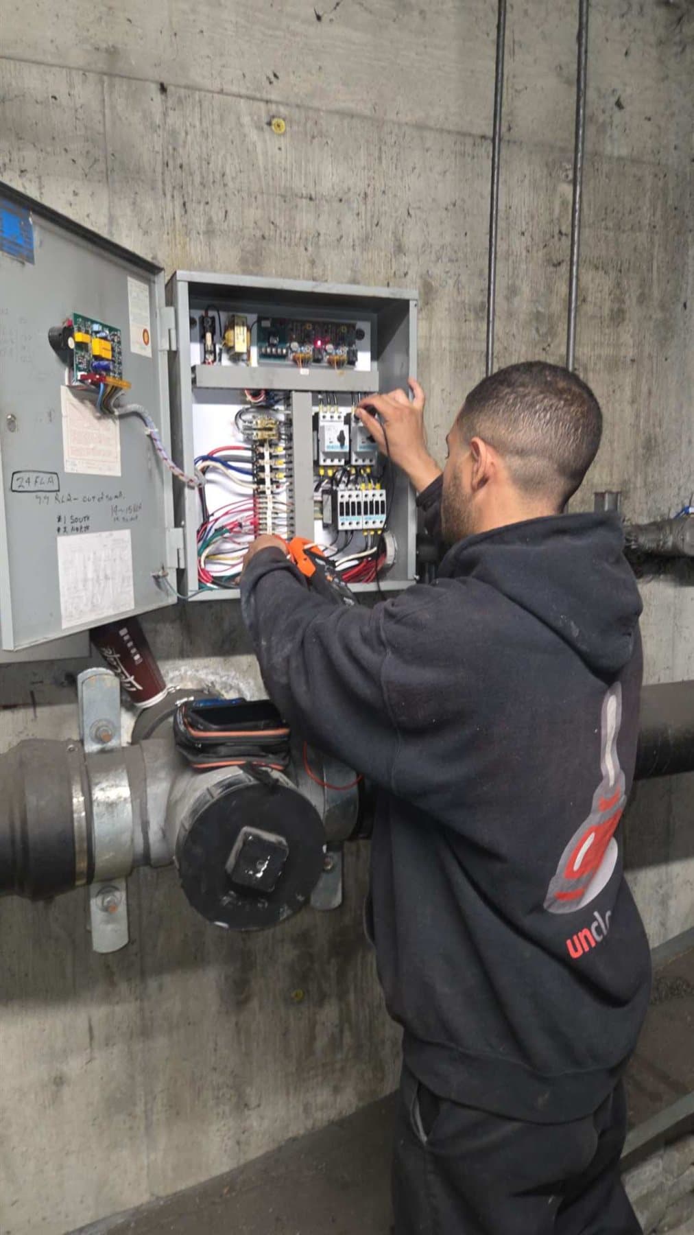 Technician testing an open sump-pump control panel