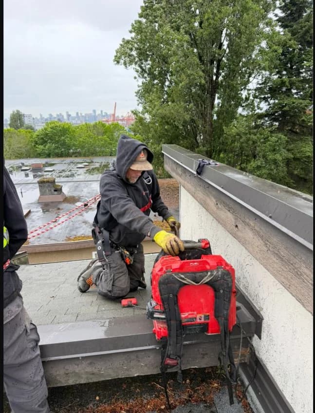Technician positioning drain-clearing equipment at a roof stack