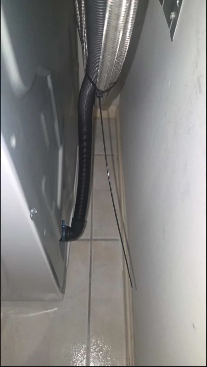Washing-machine hoses routed behind the appliance without visible kinking